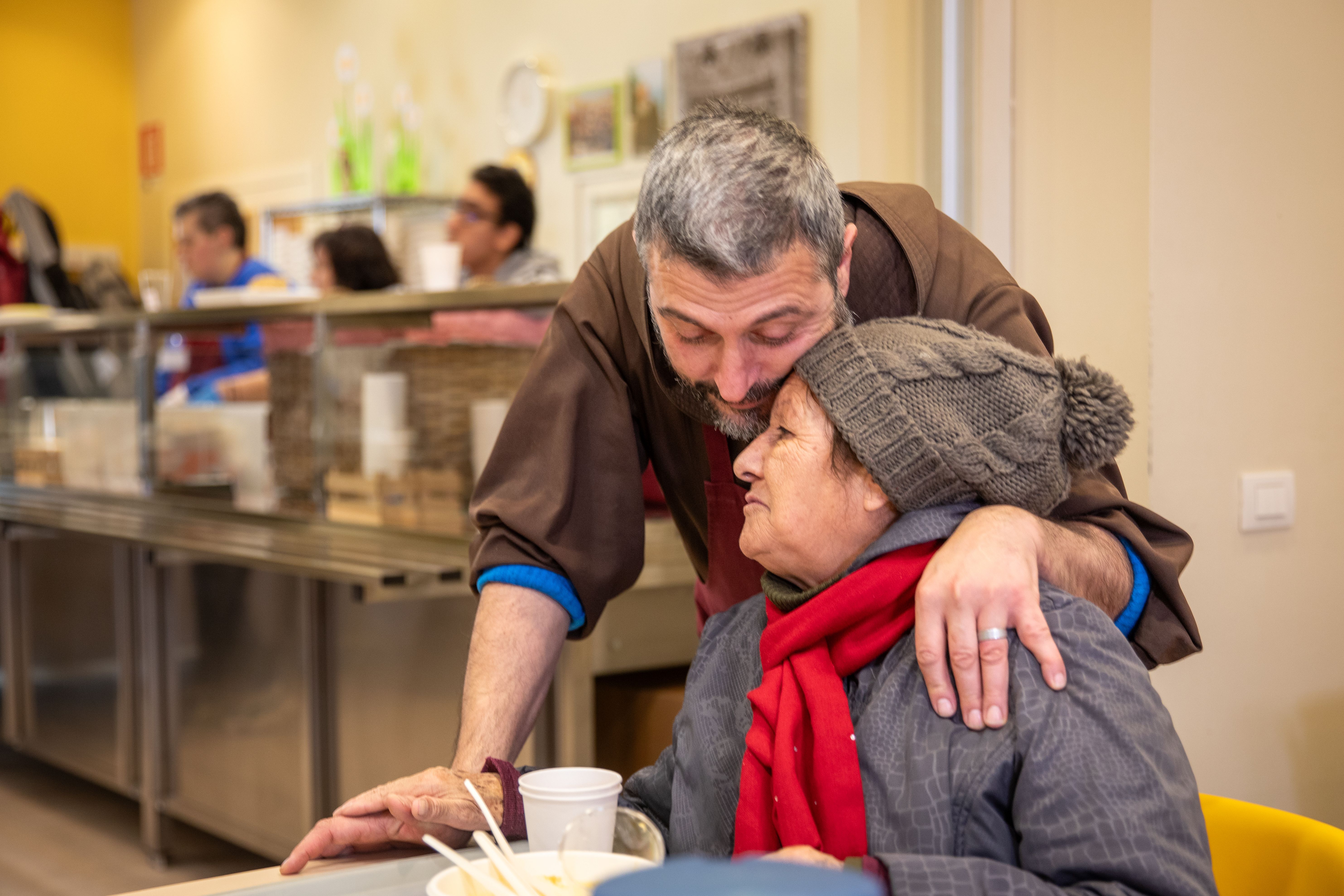 Un frate abbraccia una frequentatrice della mensa