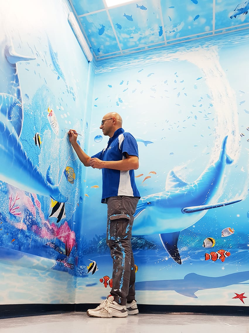 L'artista Silvio Irilli, fondatore di "Ospedali dipinti" mentre colora un muro di un reparto /Ospedali dipinti