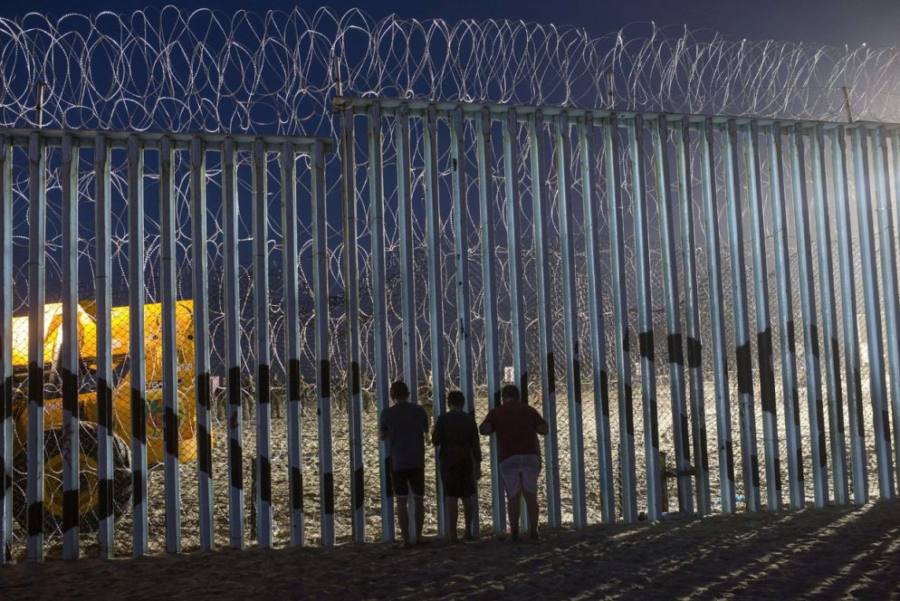 Bambini osservano i movimenti della polizia di frontiera a Tijuana (Ansa)