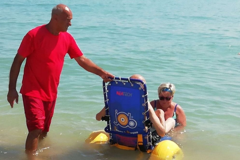Il bagno di un disabile con una sedia speciale nel mare di Porto Potenza Picena