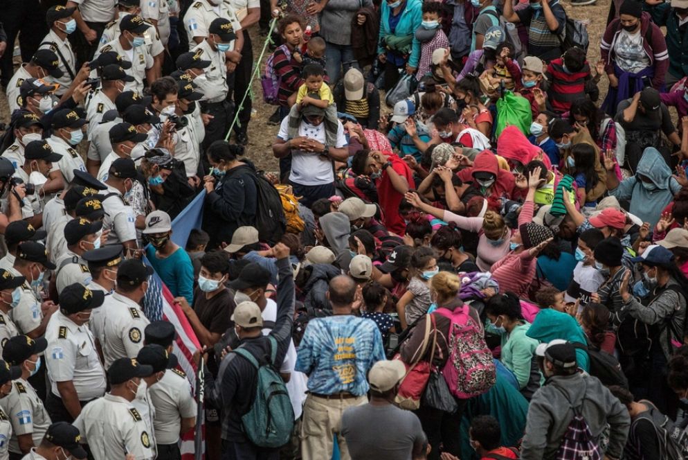I migranti partiti dall'Ecuador in preghiera davanti alla polizia nel villaggio di Vado Hondo, in Guatemala, che ha bloccato il passaggio della carovana - Ansa