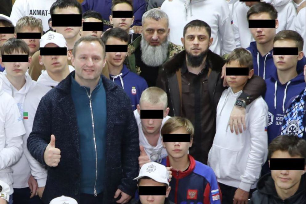 Un gruppo di adolescenti ucraini con funzionari russi e, al centro con la barba bianca, il comandante dei corpi speciali ceceno Zamyd Chalayev