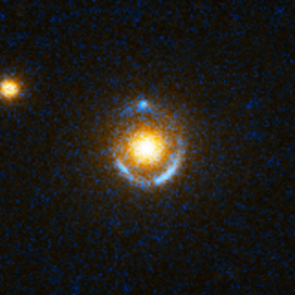 Lente gravitazionale. Le linee azzurre sono il risultato di un oggetto posto dietro il cuore della galassia (gialla) che ha subito l’effetto di lente gravitazionale