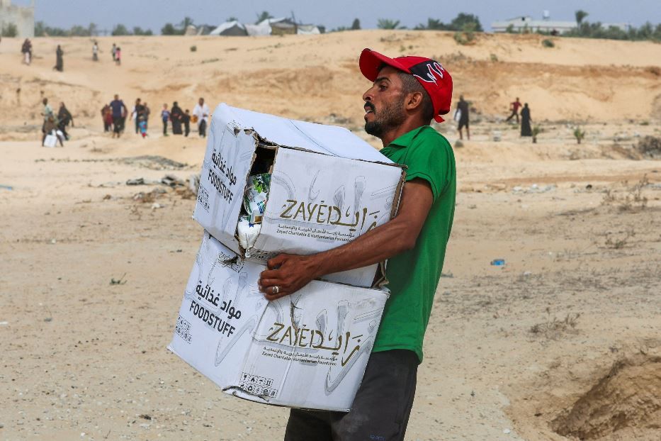 Un palestinese porta via i pacchi di aiuti che è riuscito a raccogliere presso un centro della Striscia - .