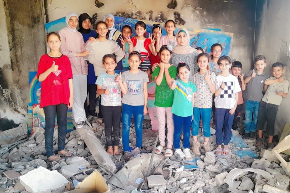 L'artista Maysa Yousef nel suo atelier bombardo a Gaza con i bambini che seguono i suoi laboratori - M.Y.