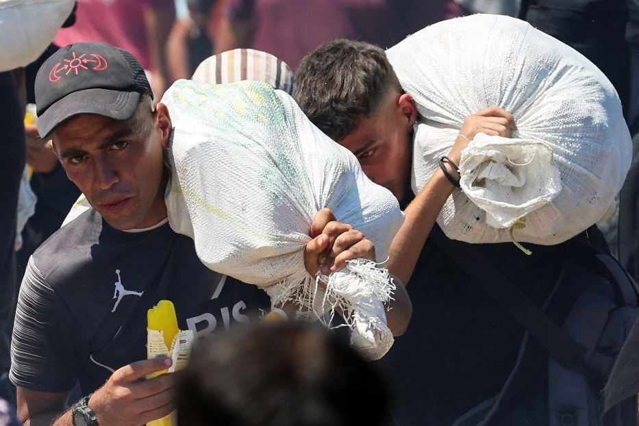 La gente di Gaza coi sacchi di farina faticosamente conquistati dopo ore di fila - .