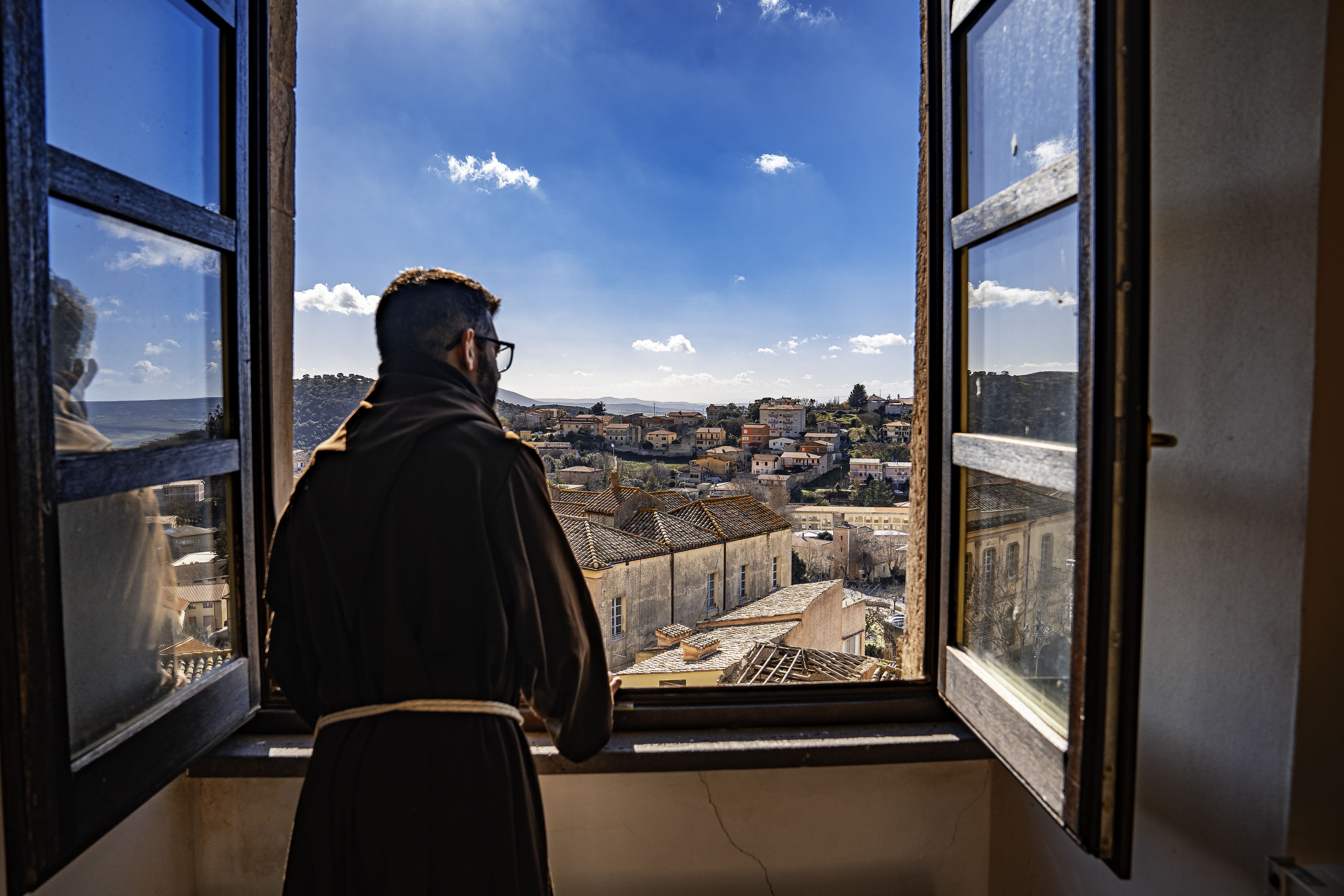 Un frate cappuccino affacciato alla finestra del convento. Il panorama sulla città di Laconi