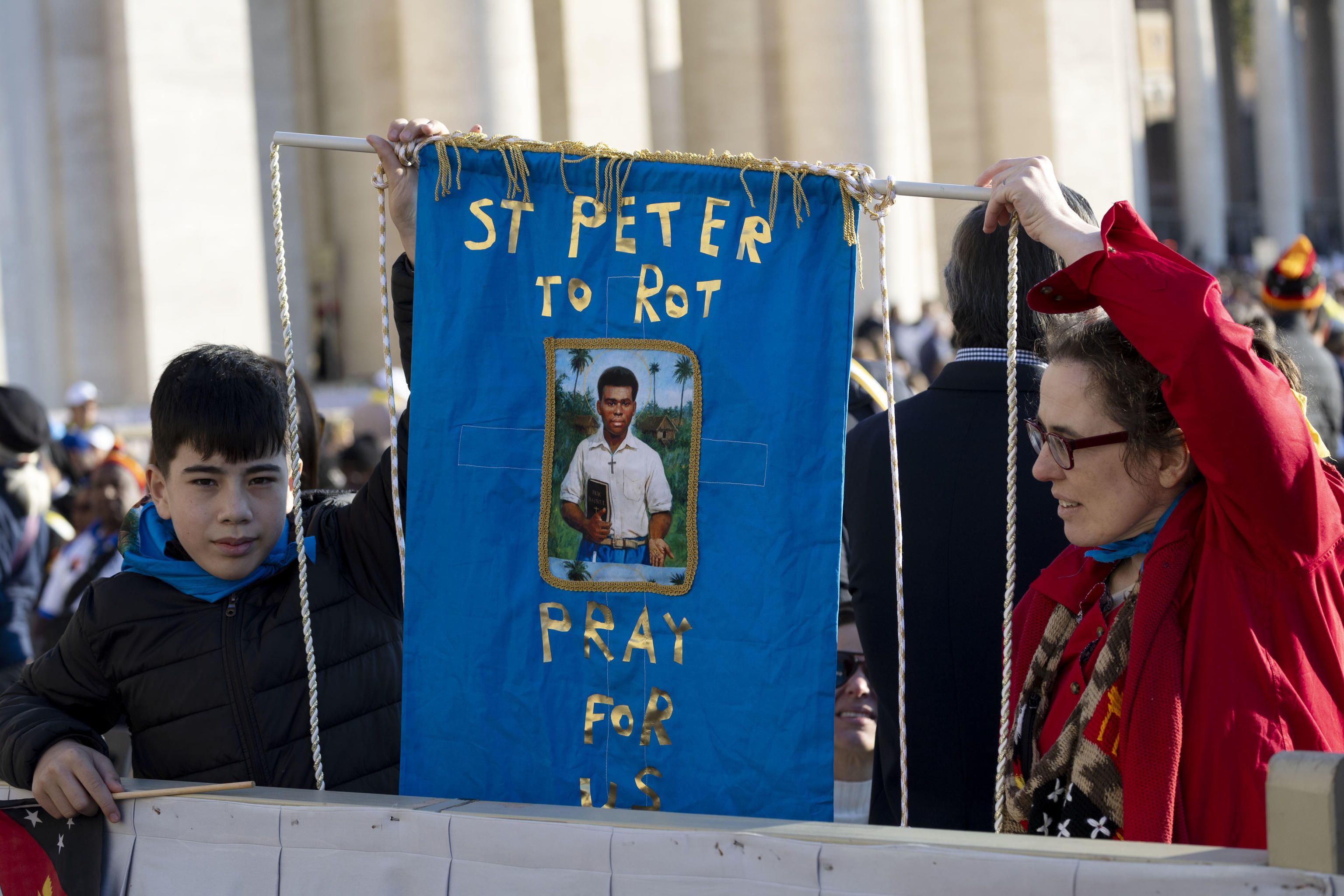 Il ritratto del catechista Pietro To Rot, primo santo della Papua Nuova Guinea, tenuto da due pellegrini in piazza San Pietro durante la Messa di canonizzazione presieduta da Leone XIV / ANSA