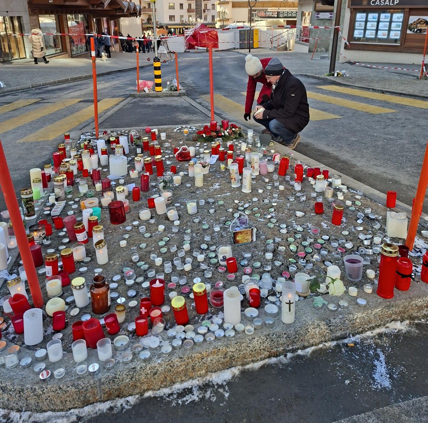 Alcune persone lasciano candele davanti al bar "Le Constellation", a Crans-Montana