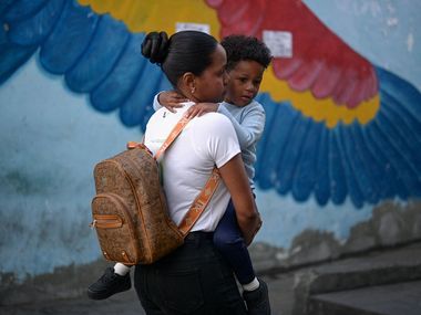 Un bimbo in braccio a una giovane donna nel giorno della riapertura delle scuole a Caracas, dieci giorni dopo il blitz anti-Maduro degli Usa / Reuters