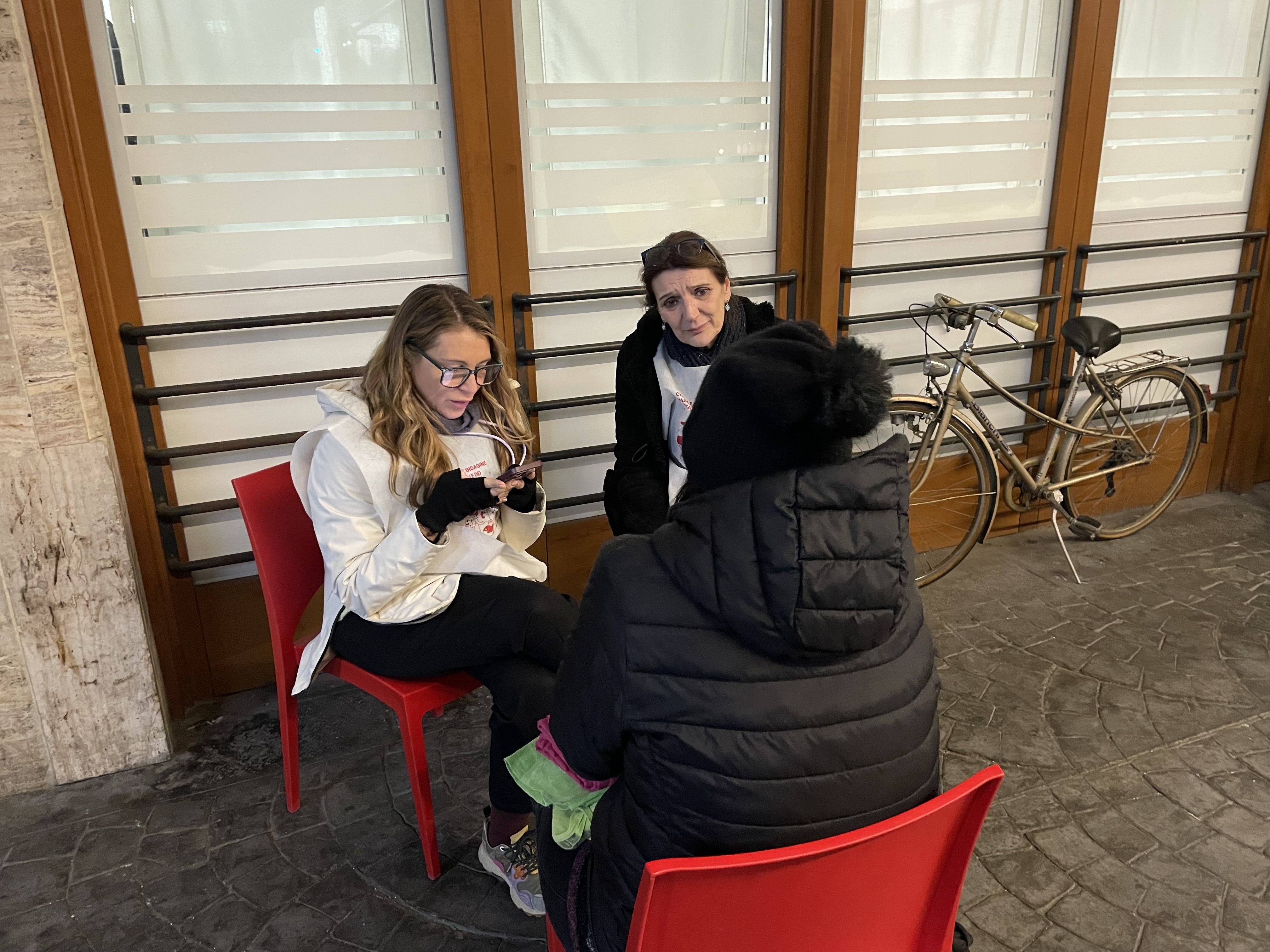 Una ospite dell’ostello della Caritas di Roma “Don Luigi Di Liegro” mentre viene intervistata all’esterno della struttura da due volontarie della rilevazione nazionale&nbsp;