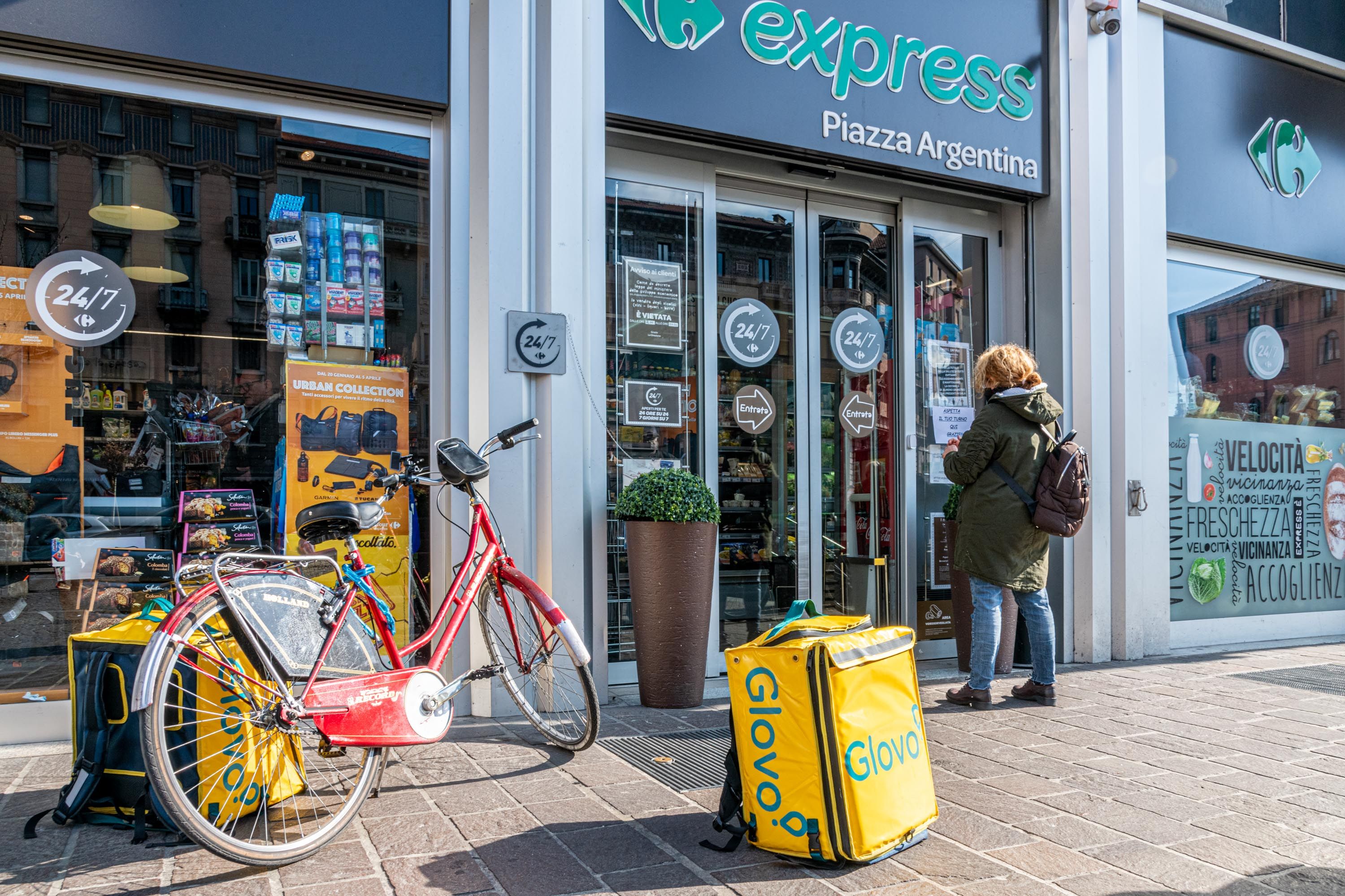 La bicicletta e la borsa di un rider parcheggiate davanti a un supermercato a Milano - Fotogramma 