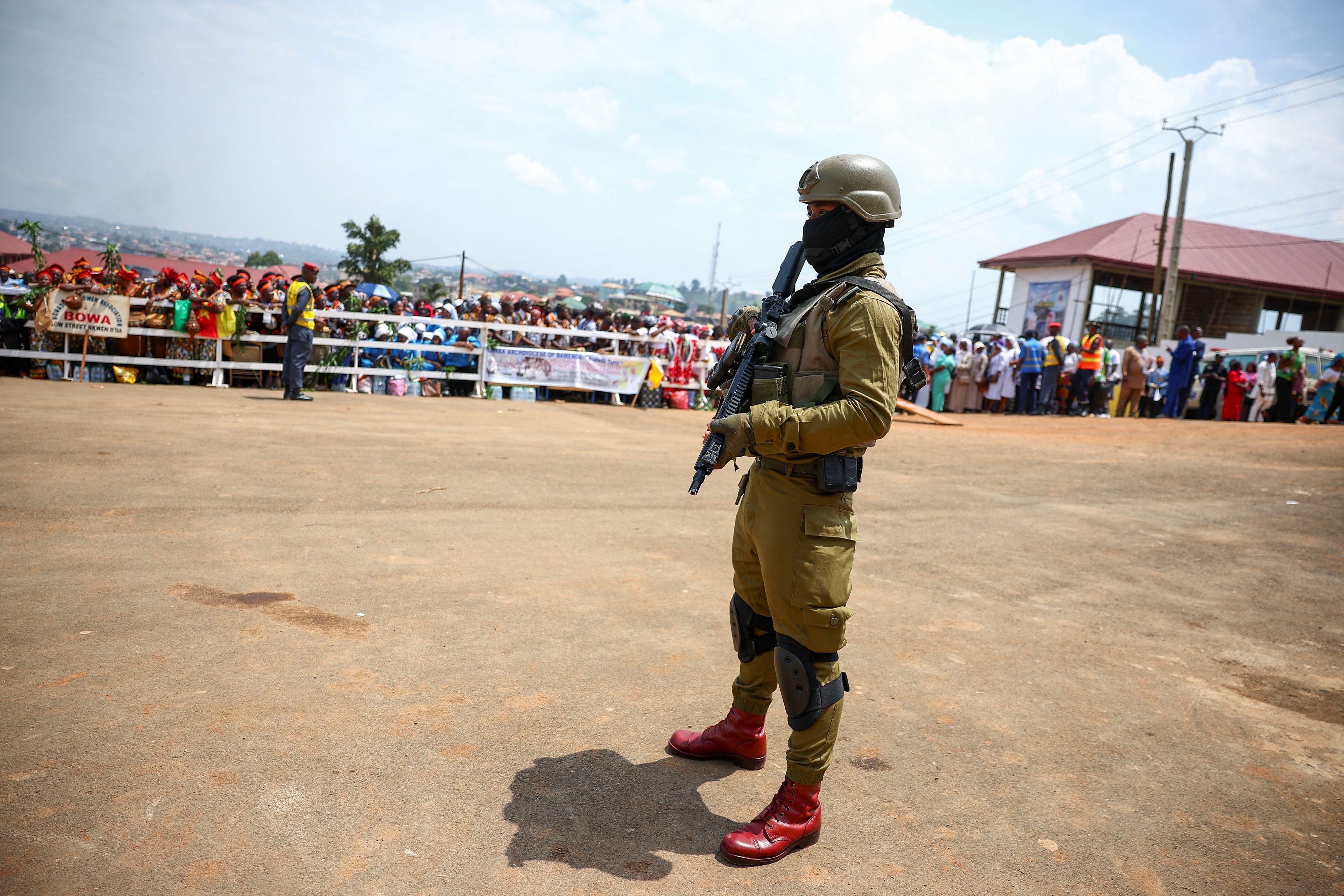 La folla in attesa di Leone XIV presidiata dai militari dell'esercito governativo a Bamenda, terra del Camerun dove è in corso da 9 anni la guerra civile / REUTERS