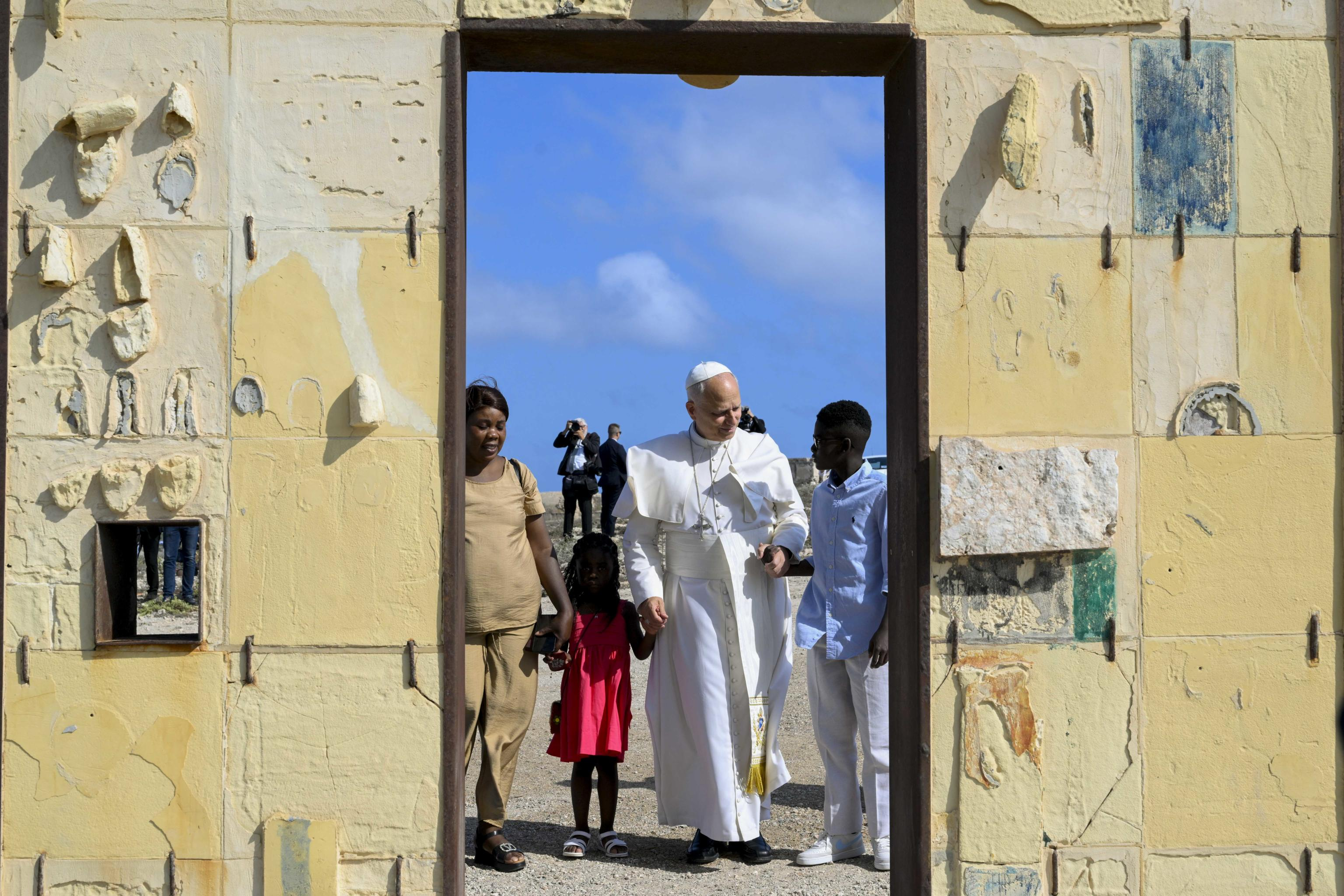 A Lampedusa papa Leone XIV attraversa la Porta d'Europa affacciata sul mare Mediterraneo con due bambini arrivati sui barconi / Vatican Media 