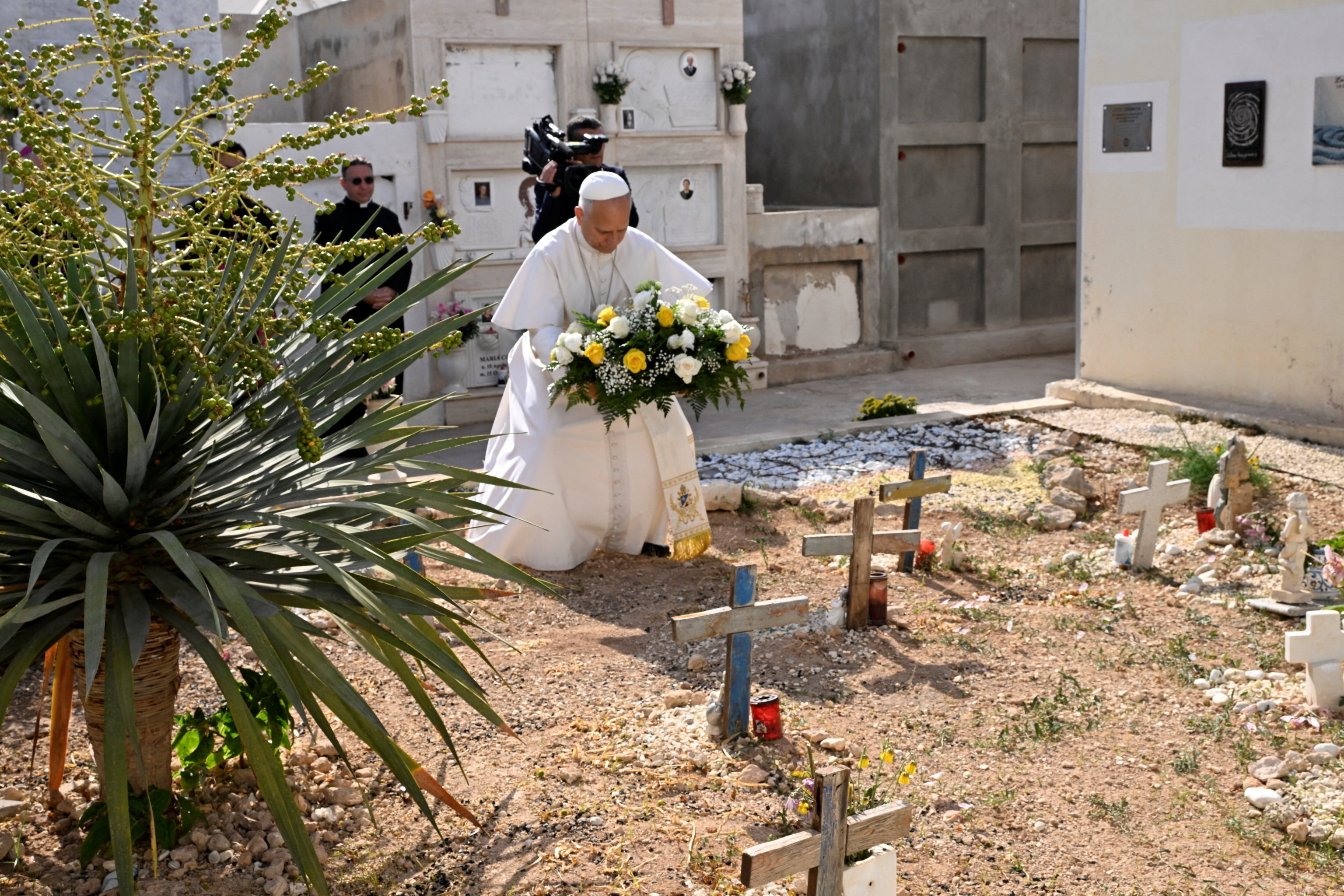 Il Papa depone i fiori davanti alle tombe dei migranti morti nei naufragi e sepolti nel cimitero di Lampedusa / ANSA