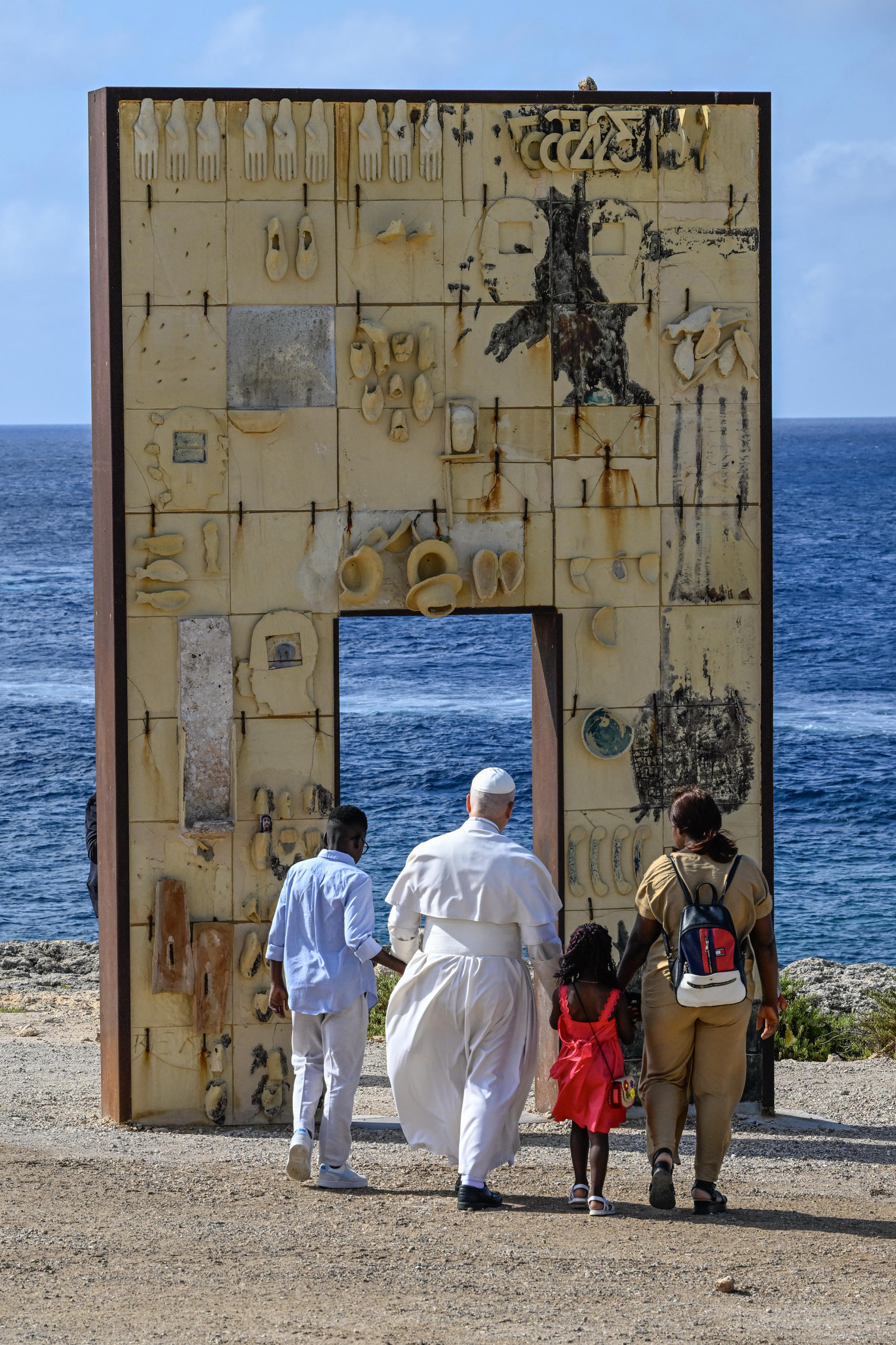 A Lampedusa papa Leone XIV attraversa la Porta d'Europa affacciata sul mare Mediterraneo con due bambini arrivati sui barconi / ANSA