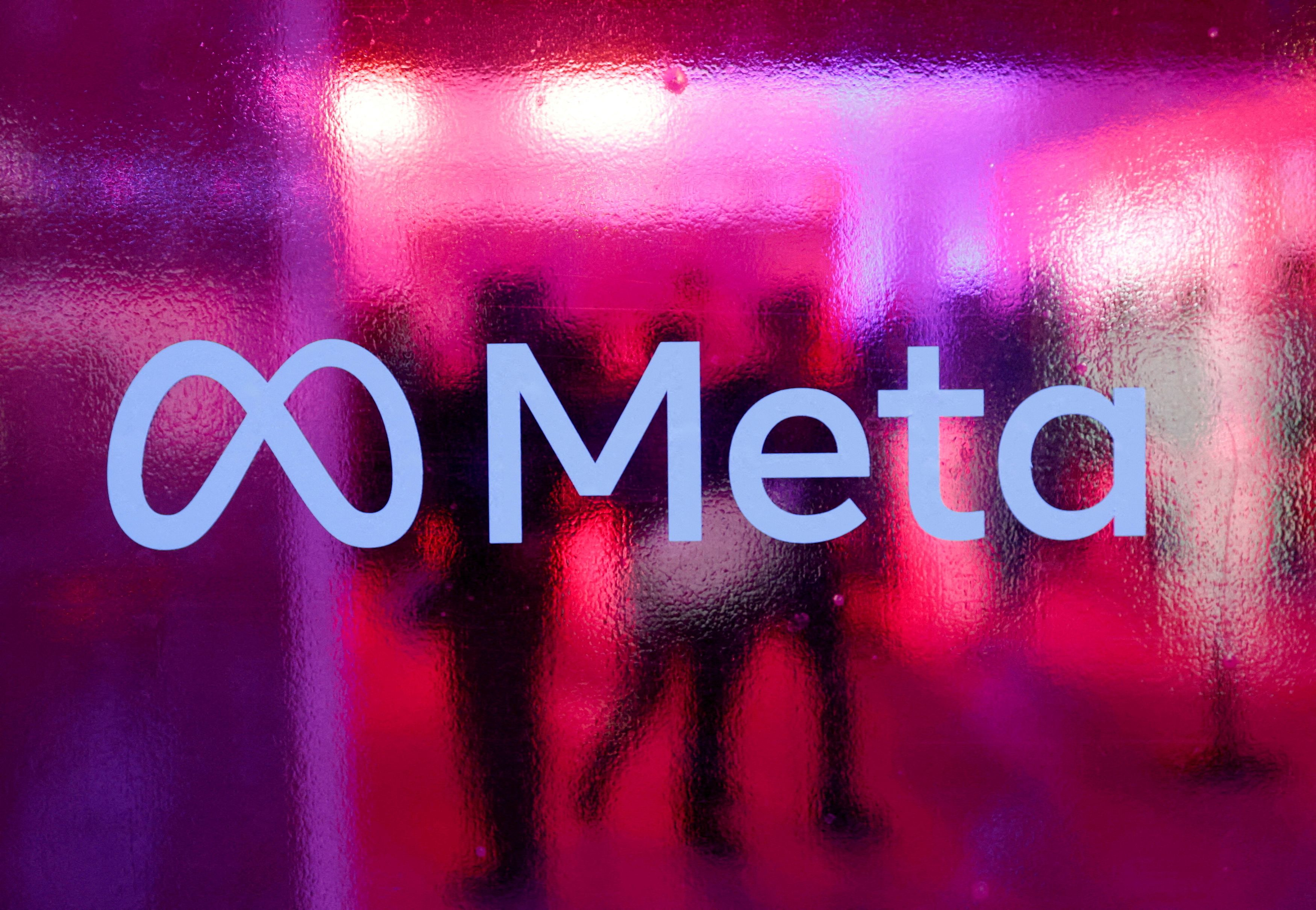 People walk behind a logo of Meta Platforms during a conference in Mumbai, India, September 20, 2023. REUTERS/Francis Mascarenhas/