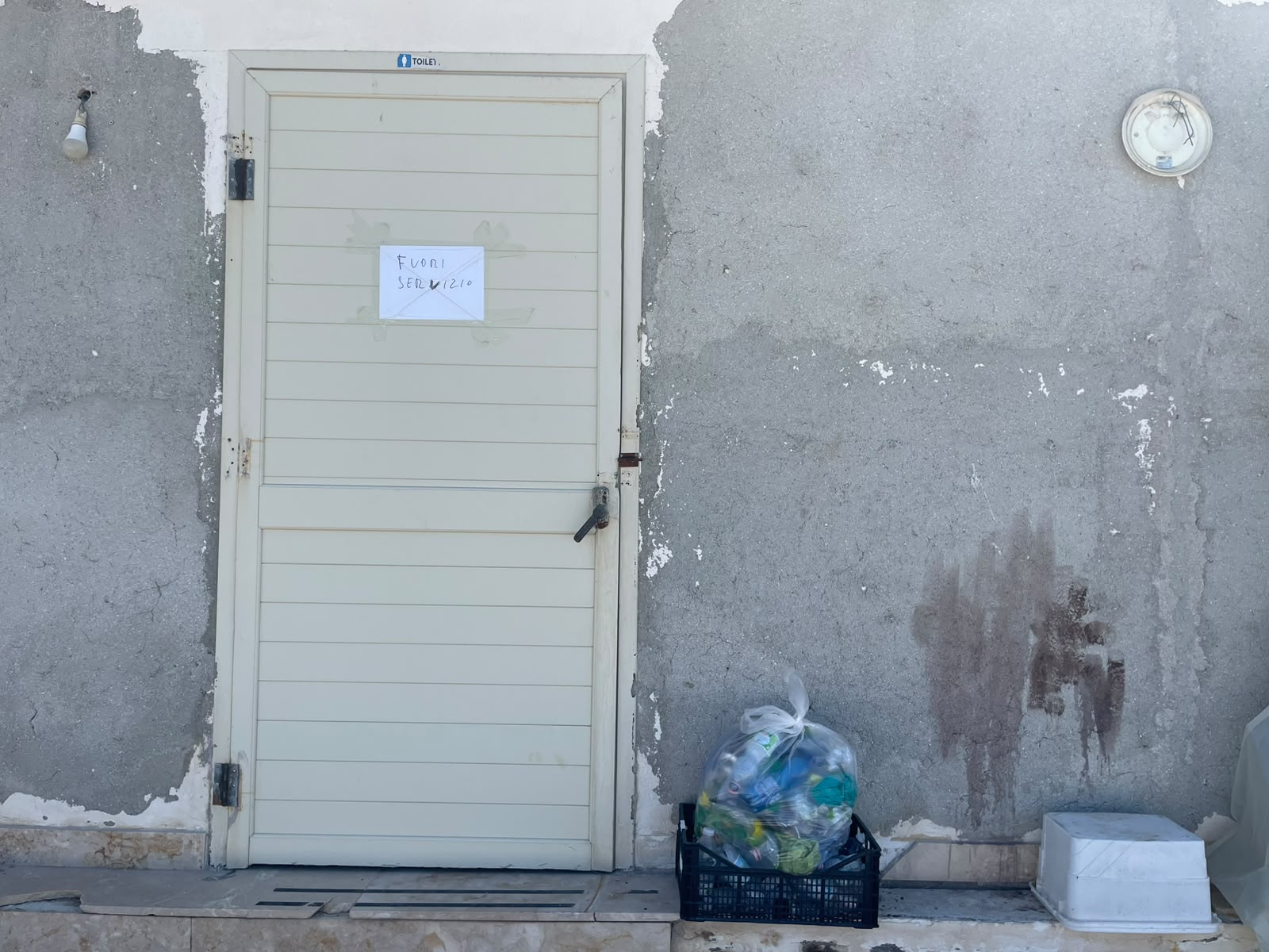Il cartello "fuori servizio" appeso sulla porta dei servizi igienici al molo "papa Francesco" / MEDITERRANEAN HOPE