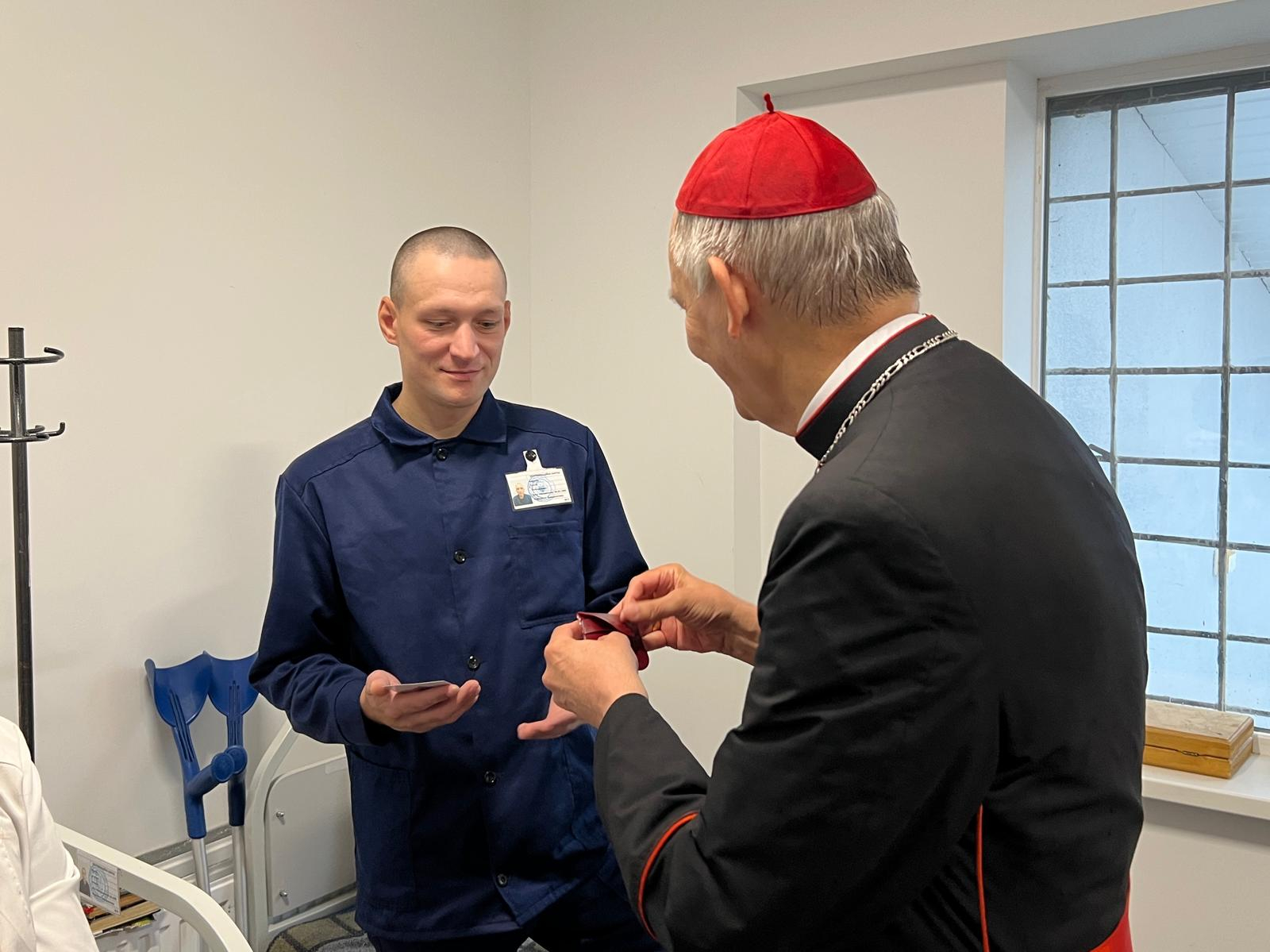 Il cardinale Zuppi dona i regali del Papa a uno dei prigionieri nell'infermeria del campo di detenzione in Ucraina / FOTO ESCLUSIVE DI GIACOMO GAMBASSI