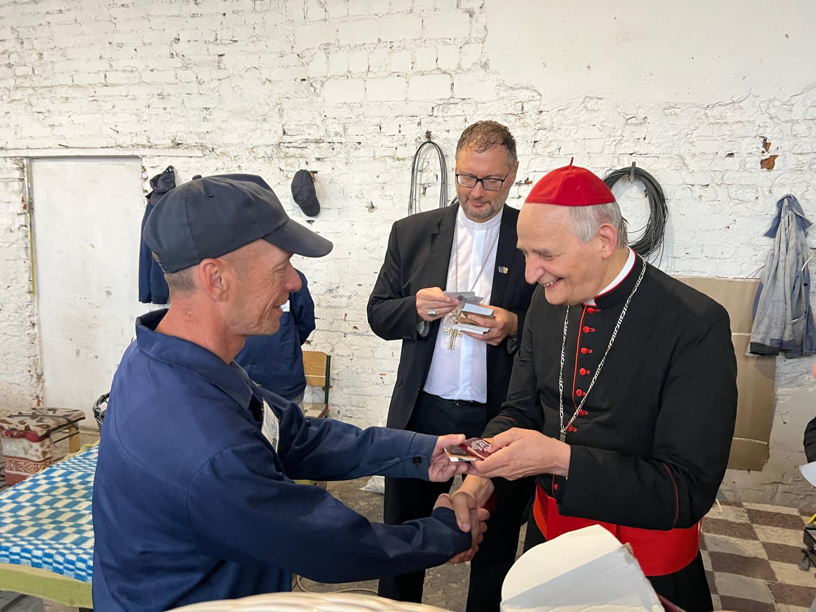 Il cardinale Zuppi dona i regali del Papa a uno dei prigionieri nello spazio di lavoro del campo di detenzione in Ucraina / FOTO ESCLUSIVE DI GIACOMO GAMBASSI